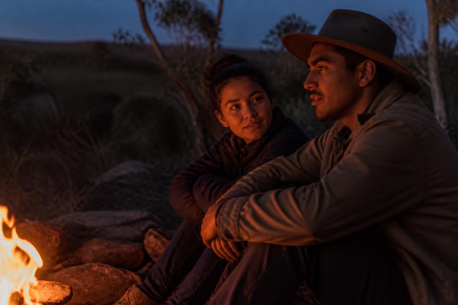 A couple sitting close by a campfire at dusk
