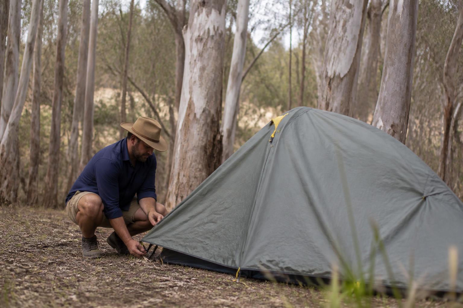 A solo camper pitching his tent among gum trees